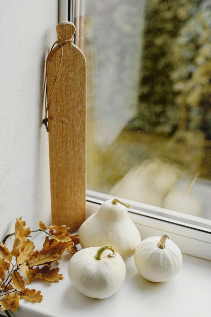 Autumn decorations with pumpkins and autumn leaves on the window.