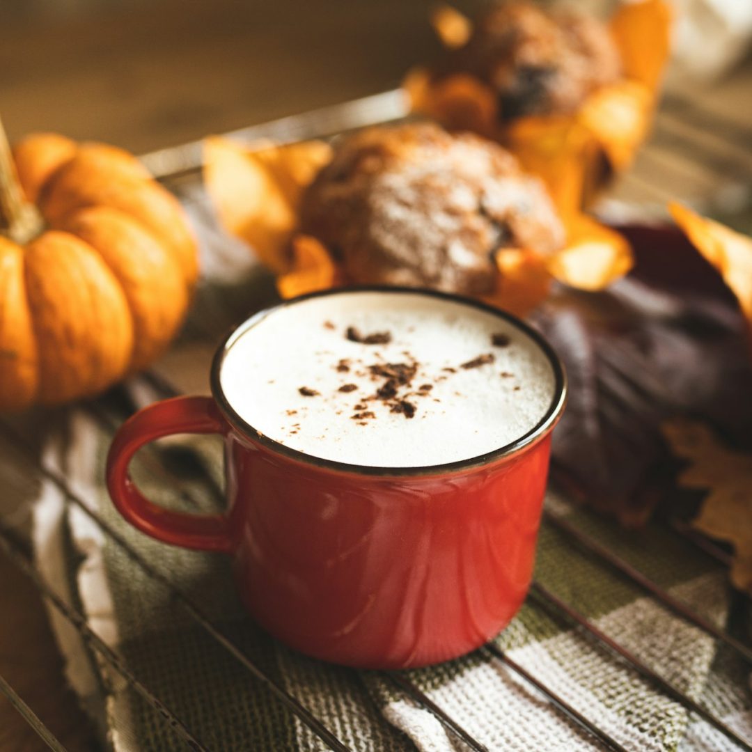 Spicy cocoa and cupcake on the table. Hot drink in a red mug. Autumn drink and homemade cakes.